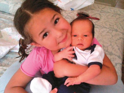 Isabella cuddling her new baby brother