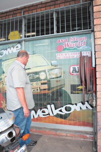 Naardus Jooste inspects his shop front glass window which was broken on Monday night