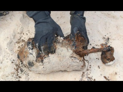An explosives expert examines a ‘smoke float’ found buried in the lake bed