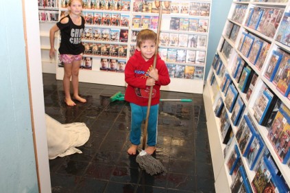Two children help to mop the floor at the video shop