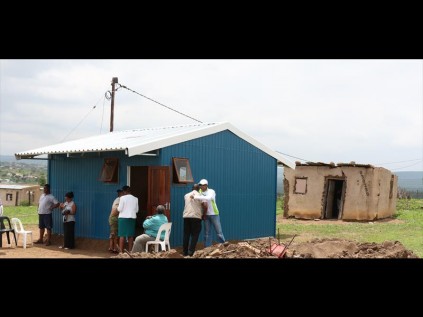 The bright blue steel house stands in stark contrast to the rundown shack in the background, in which the orphan boy was living