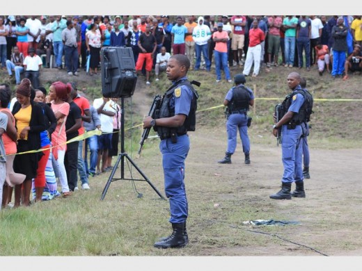 Police officers armed with R5 assault rifles stand guard as government officials address a crowd of protesters in iSithebe, March 2016 Photo - Kyle Cowan