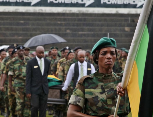 An uMkhonto We Sizwe member carries an ANC flag ahead of a procession carrying the coffin of late Struggle stalwart, Riot Mkhwanazi. Photo - Kyle Cowan